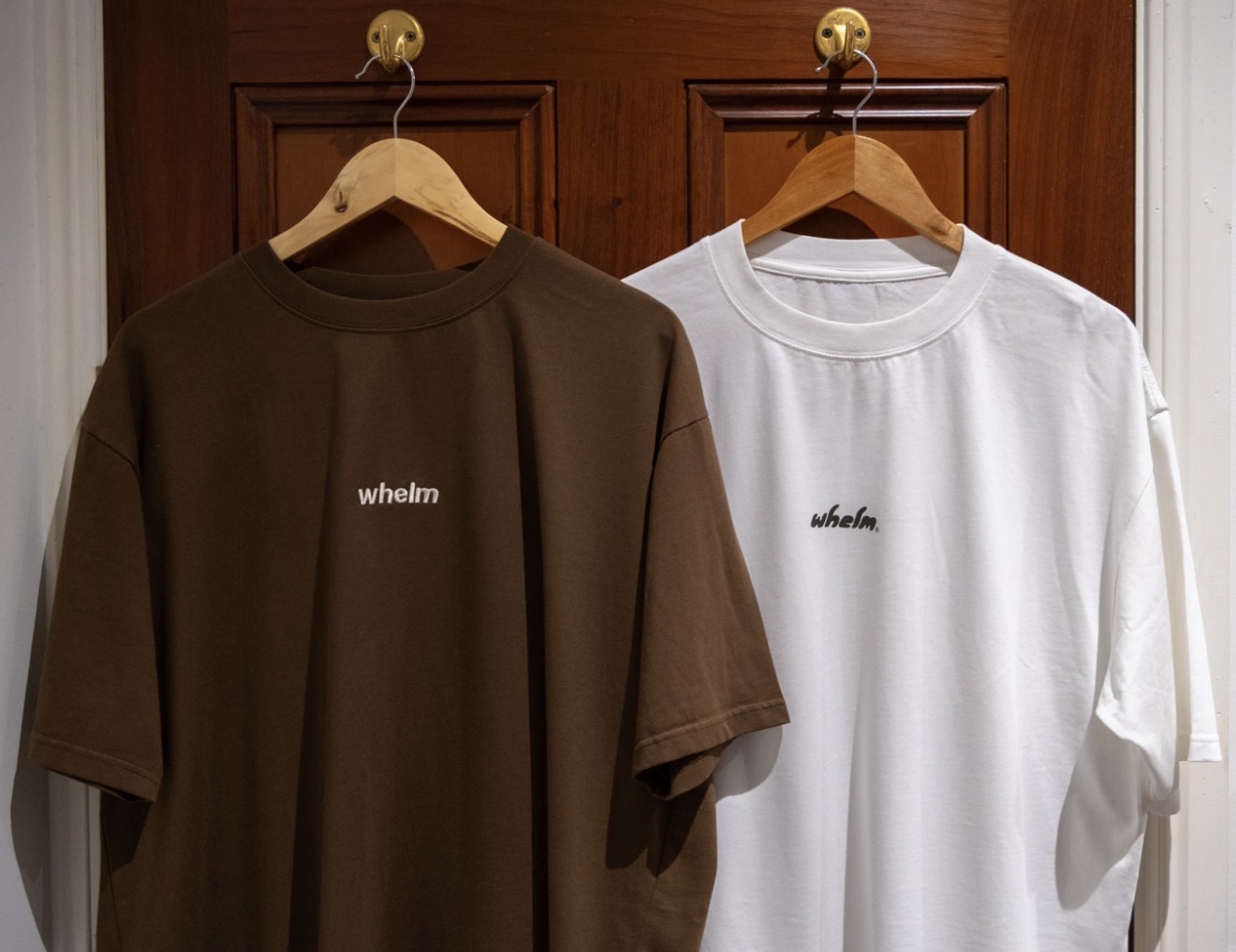 whelm tees in chocolate and off white, hanging on timber hangers